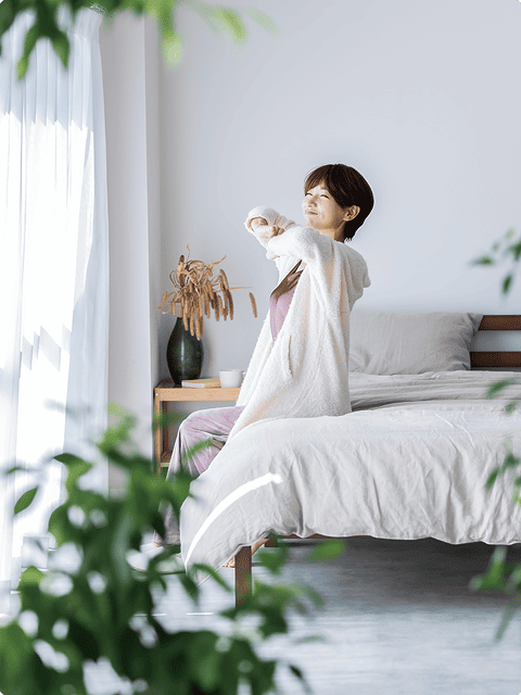 朝の光が差し込む寝室で目覚める女性